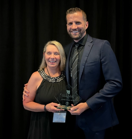 two people wearing black tie attire holding an award