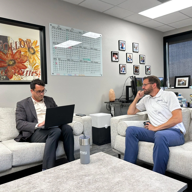 two people on couches, working on laptops