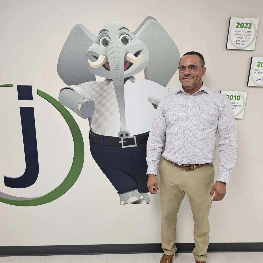 person wearing business attire, standing in front of graphic of elephant