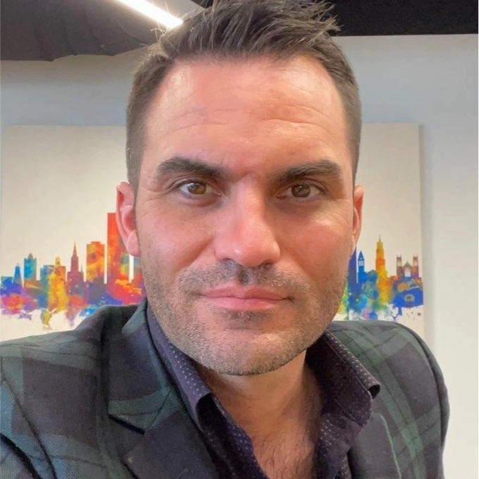 man smiling, wearing a suit